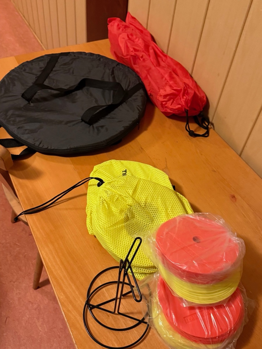 Neues Trainingsequipment auf einem Tisch: Taschen mit Ringen und Reifen, Markierungsplättchen in Rot und Gelb sowie ein Halter für die Plättchen